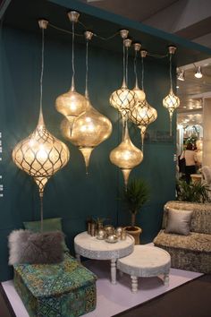 a room filled with furniture and lights hanging from it's ceiling, next to a green wall