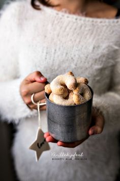 a woman holding a cup filled with sugared doughnuts on top of it