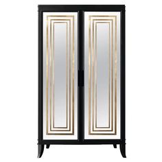 an armoire with mirrored doors and gold trimmings on the front, in black