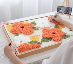 a woman is painting flowers on a canvas with acrylic paint and crochet