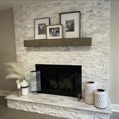 a white brick fireplace with two pictures on the mantel and some vases next to it