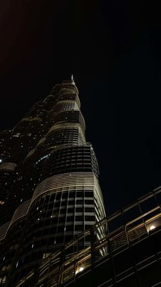 a very tall building lit up in the dark night sky with lights on it's sides