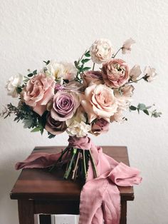 a bouquet of flowers sitting on top of a wooden table next to a card holder