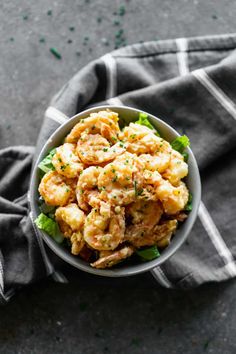 a bowl filled with shrimp and lettuce on top of a black table cloth