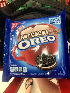 a bag of chocolate oreo sitting on top of a table next to a person's feet