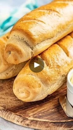 bread and butter are sitting on a wooden cutting board next to a bowl of dip