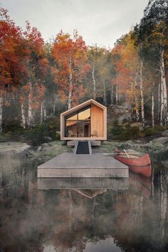 a boat is sitting in the water next to a small cabin on a lake with trees around it