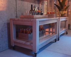 an empty bar with bottles on the top and shelves behind it, in front of a concrete wall