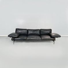 a black leather couch sitting on top of a white floor next to a gray wall