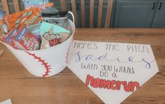 a bucket filled with candy sitting on top of a table next to a paper sign