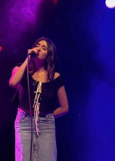 a woman singing into a microphone on stage