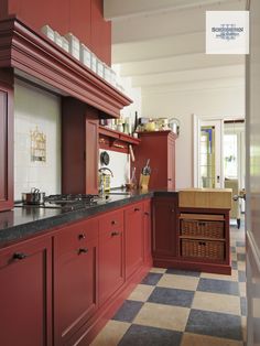 a kitchen with red cabinets and checkered flooring on the tile counter tops, along with an oven