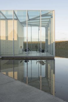 an empty glass building sitting on top of a body of water