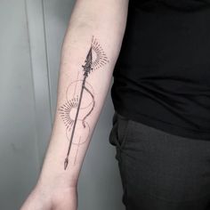 a person with a tattoo on their arm that has an arrow and sunburst