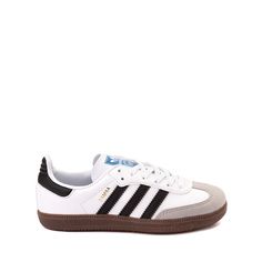 a white and black adidas sneakers with brown soles on the bottom, against a white background