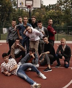 a group of young men standing and sitting on top of a basketball court