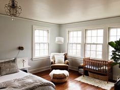 there is a bedroom with two windows and a baby crib in the middle of the room