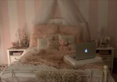 a laptop computer sitting on top of a bed in a room with pink and white striped walls