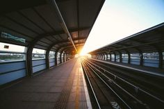 the sun shines brightly through an empty train station as it sits on its tracks