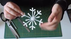 someone cutting out snowflakes with scissors on a cutting board