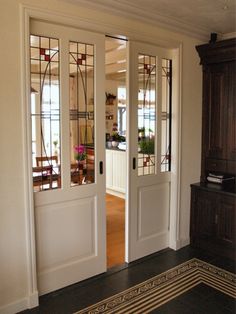 two white doors with stained glass panels in a room next to a dresser and mirror