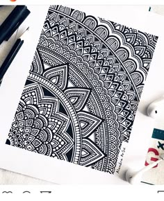 an intricate black and white drawing on paper next to some markers, pens and scissors