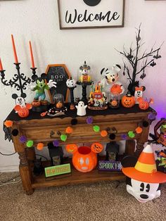 a table with halloween decorations on it and candles in the corner, along with a sign that says welcome