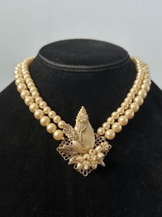 Vintage 1950s Double Strand Faux Pearl Collar Choker Necklace Filigree Leaf Pendant Adjustable 16.5" Circa 1940s-1950s. Beautiful double strand faux pearl collar necklace, with a filigree leaf detail center pendant also embellished with faux pearls, seed pearls, and rhinestones. Necklace measures approximately 16.5 inches long and has a hook closure. Adjustable length down to approximately 14.5" inches. Center pendant measures approximately 2 inches long by 1.6 inches wide. In good condition with no noticeable flaws. Please see all photos. Rhinestones Necklace, Pearl Collar, Collar Choker, Choker Collar, Seed Pearl, Leaf Pendant, Collar Necklace, Vintage 1950s, Faux Pearl