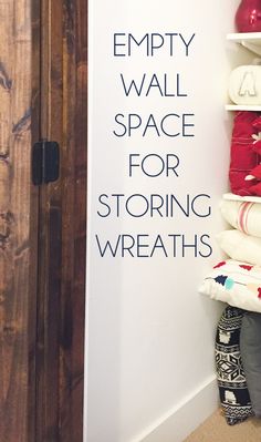 the empty wall space for storing wreaths is displayed in front of a wooden door