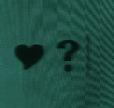 the shadow of a heart and a question mark in front of a green screen background