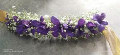 purple flowers and baby's breath are arranged on the edge of a silver surface