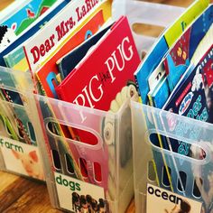 plastic bins filled with books on top of a wooden table