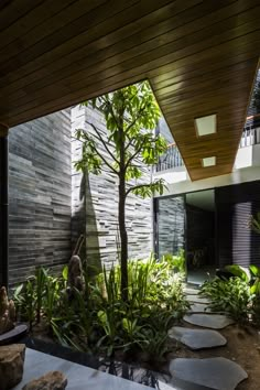 the inside of a house with plants and rocks in front of it, as well as an outdoor dining area