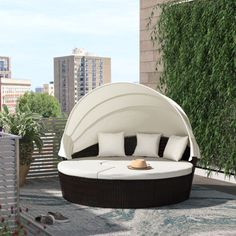 an outdoor daybed with cushions and pillows on top of a patio area in front of tall buildings