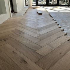 an empty room with wooden floors and large windows in the backround, looking into another room