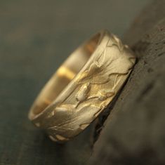 a wedding ring that is sitting on top of a piece of wood and has been engraved with leaves