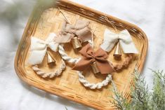 four different bows are on a wicker tray next to some green plants and branches