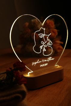 an illuminated heart with a couple's face and name engraved on it, sitting on a table