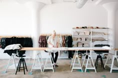 a woman standing in front of a table with clothes on it