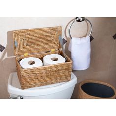 two rolls of toilet paper in a wicker basket on the back of a toilet