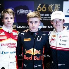 three young men standing next to each other in front of a red bull wallpaper