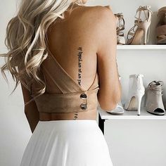 the back of a woman's dress with words tattooed on her left shoulder and bottom part