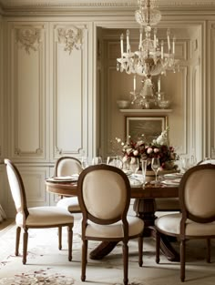 an elegant dining room with chandelier and table set for four people in it