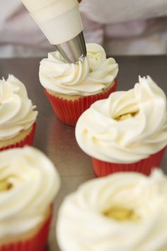 a person is making cupcakes with white frosting