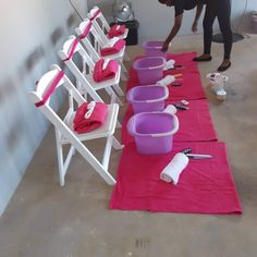 a man standing next to a table filled with purple buckets and pink napkins