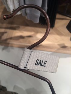 a sale label is hanging on a clothes rack