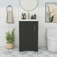 a white toilet sitting next to a black cabinet in a bathroom under a round mirror