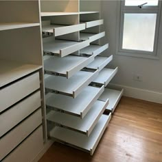 an empty closet with drawers and shelves in front of a window on the floor next to a wooden floor