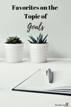 three potted plants sitting on top of a table next to a notebook and pen