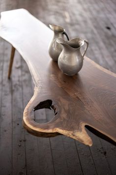 a wooden table with two silver vases on it